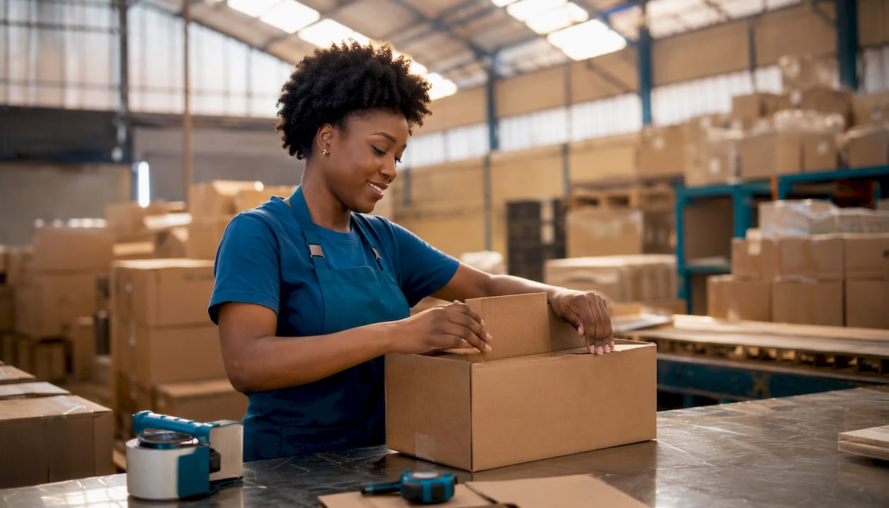 Hands assembling shipping box in warehouse