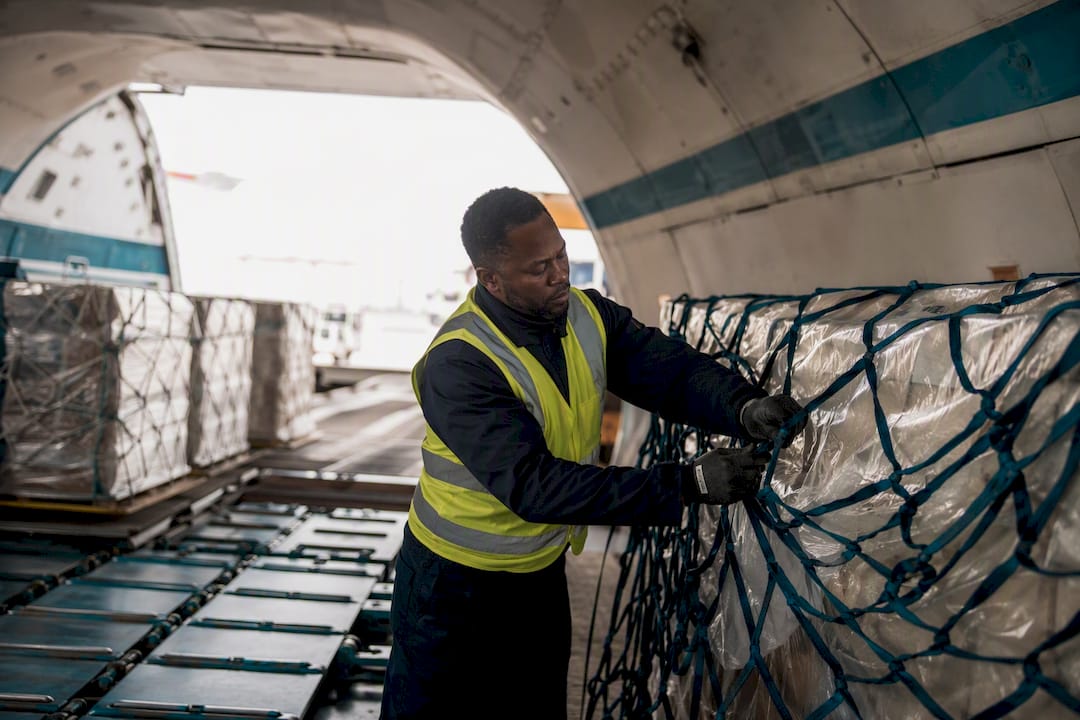 Worker securing air freight pallet in cargo hold