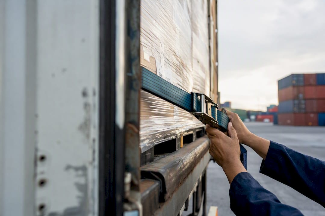 Hands securing cargo straps on freight truck trailer