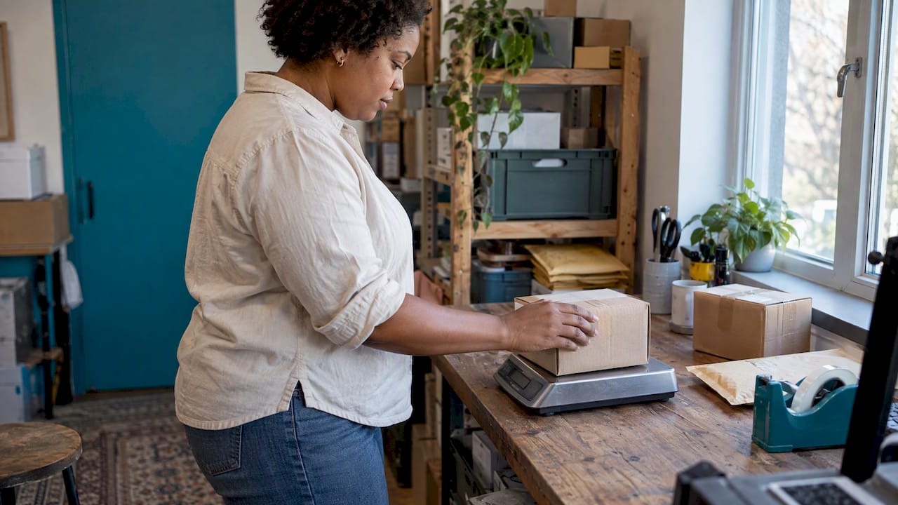 Seller weighing small parcels on a postal scale